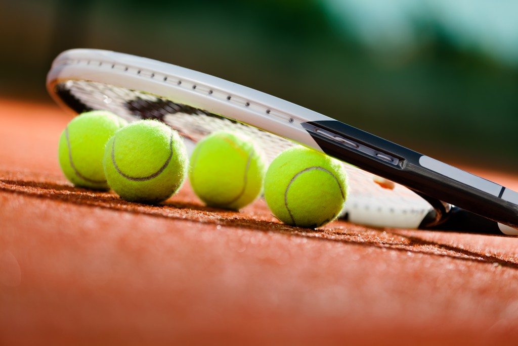Tennis racket and balls on the clay tennis court