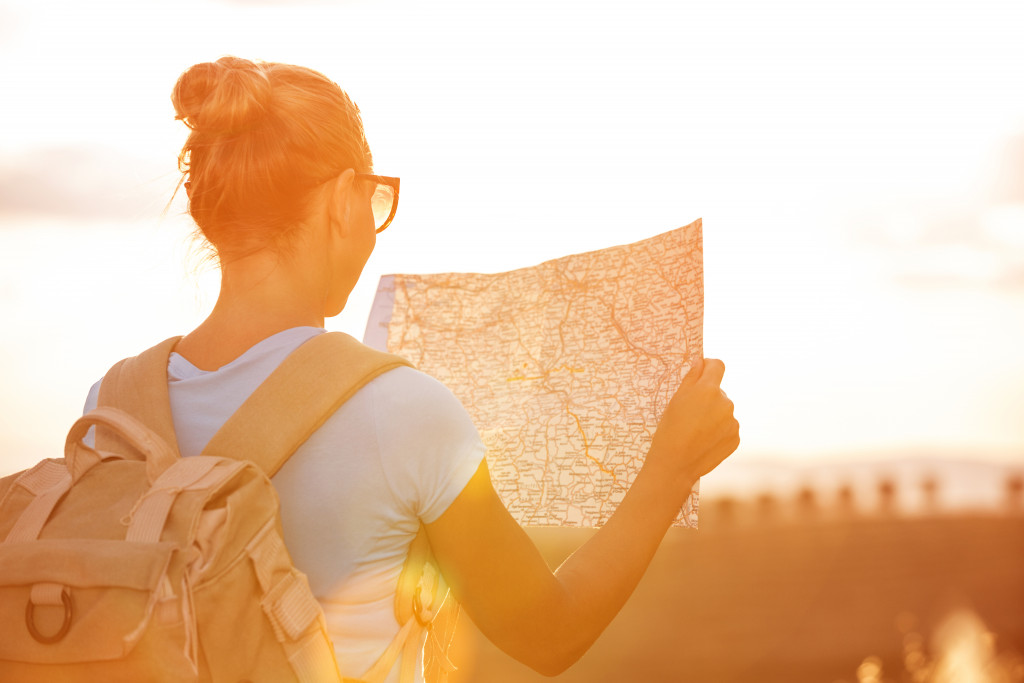 woman with glasses looking at map in the sunset